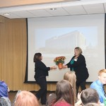 Ellen Schendel hands flowers over to a woman
